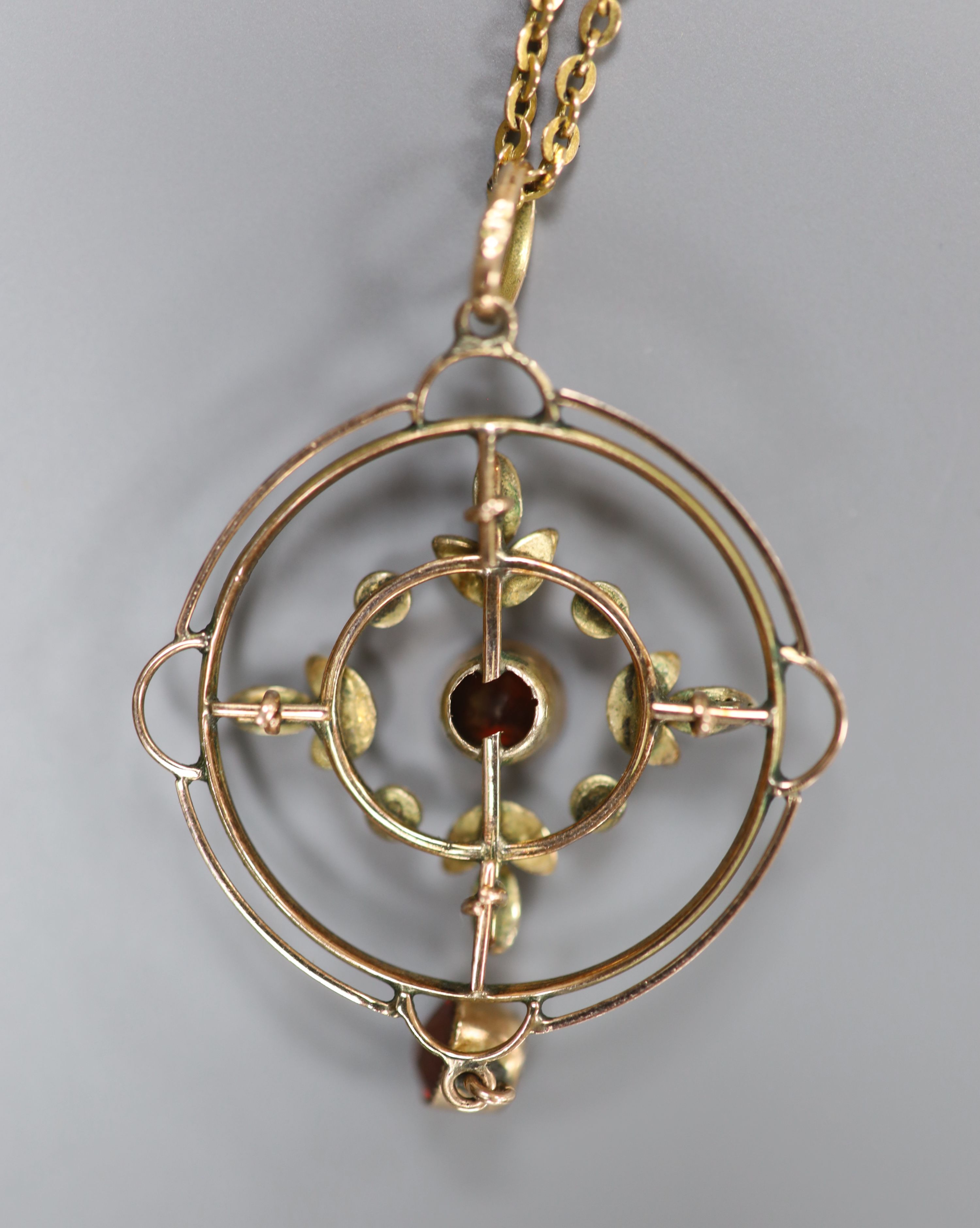 A 9ct, garnet and seed pearl set openwork circular drop pendant, 35mm, on a 9ct chain, 42cm, gross weight 4.9 grams.